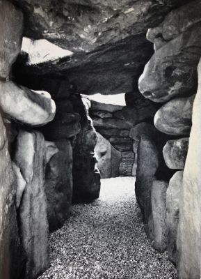 Photo of the entrance to West Kennet megalithic tomb. Irregular stone walls and  darkness.